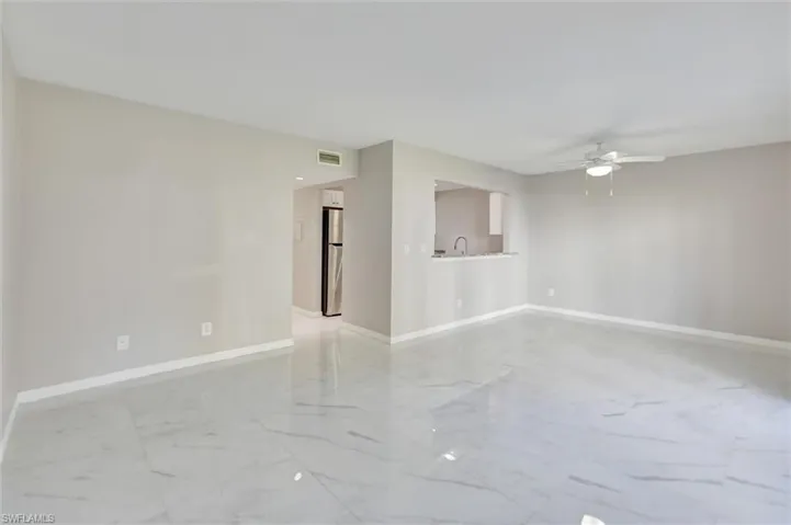 Empty room with light marble finish floors and a ceiling fan