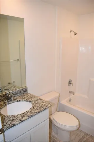 Full bathroom with bathing tub / shower combination, vanity, tile patterned flooring, and toilet