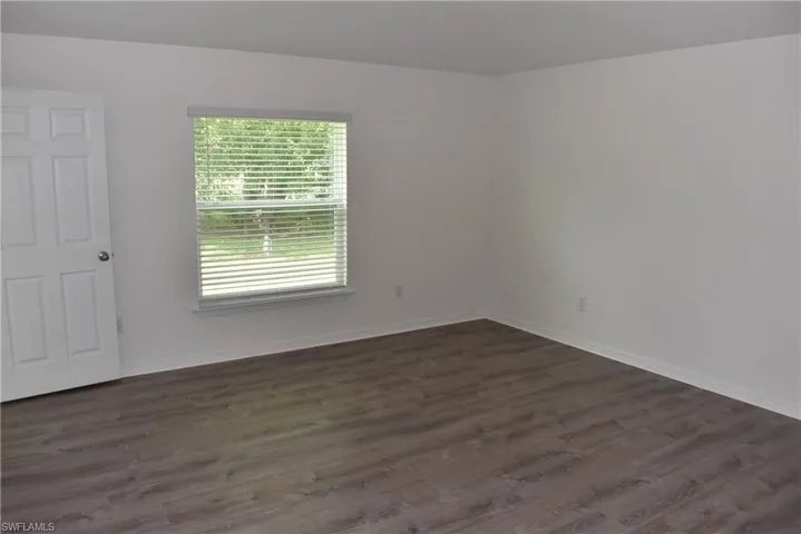 Empty room with dark wood-style floors and baseboards