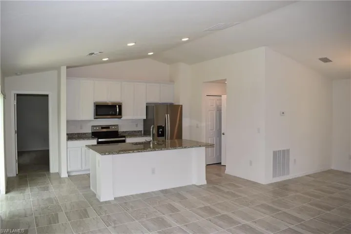 Kitchen with a center island with sink, appliances with stainless steel finishes, and light tile patterned floors