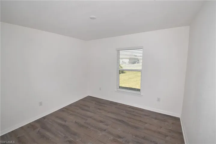 Empty room with dark wood finished floors and baseboards
