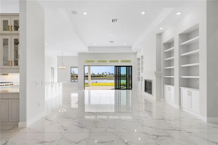 Unfurnished living room featuring an inviting chandelier, recessed lighting, built in shelves, and marble finish floor