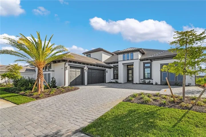 Prairie-style home featuring a tiled roof, an attached garage, decorative driveway, and stucco siding