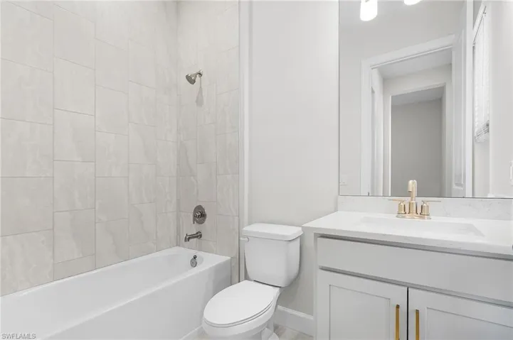 Full bathroom with vanity, baseboards, bathing tub / shower combination, and toilet