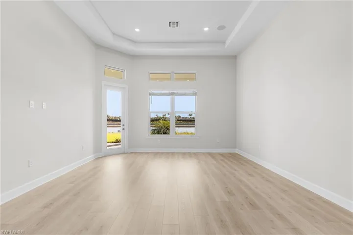Unfurnished room featuring baseboards, visible vents, a raised ceiling, and light wood-type flooring