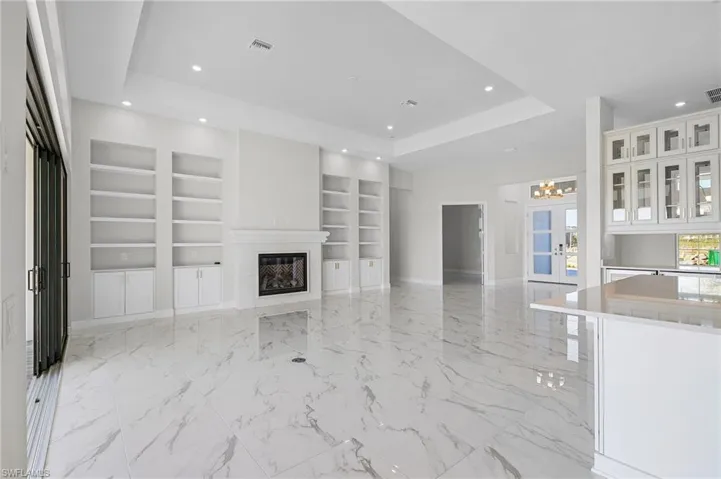 Unfurnished living room featuring visible vents, baseboards, recessed lighting, a tray ceiling, and built in shelves