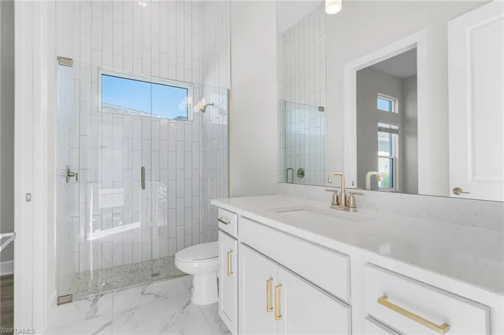 Bathroom with vanity, marble finish floor, a stall shower, and toilet