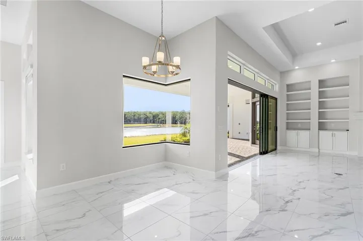 Unfurnished dining area with visible vents, marble finish floor, built in features, baseboards, and a chandelier