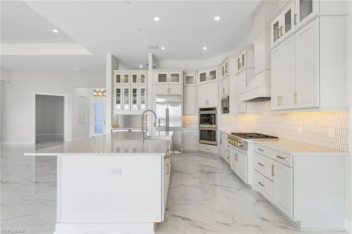 Kitchen featuring marble finish floor, an island with sink, recessed lighting, tasteful backsplash, and appliances with stainless steel finishes