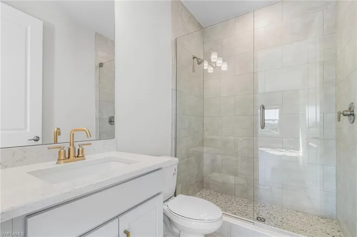Bathroom featuring toilet, a shower stall, and vanity