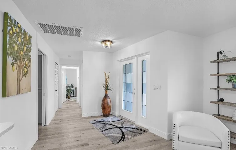 Entryway with french doors, light wood-style flooring, and a textured ceiling