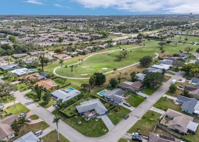 Aerial view of property and surrounding area with a local golf course and nearby suburban area