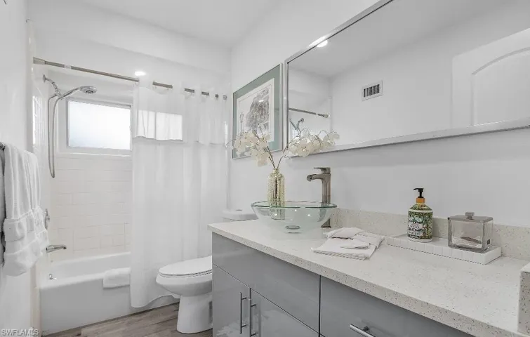 Bathroom featuring vanity, shower / bath combo, and wood finished floors