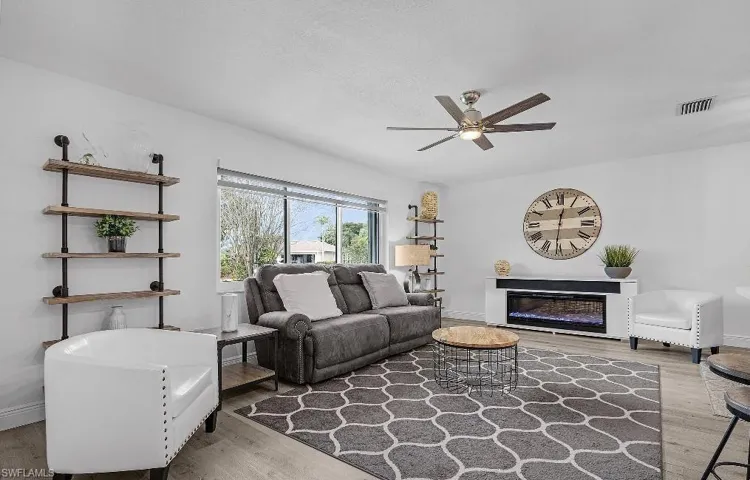 Living room with wood finished floors, a glass covered fireplace, and a ceiling fan