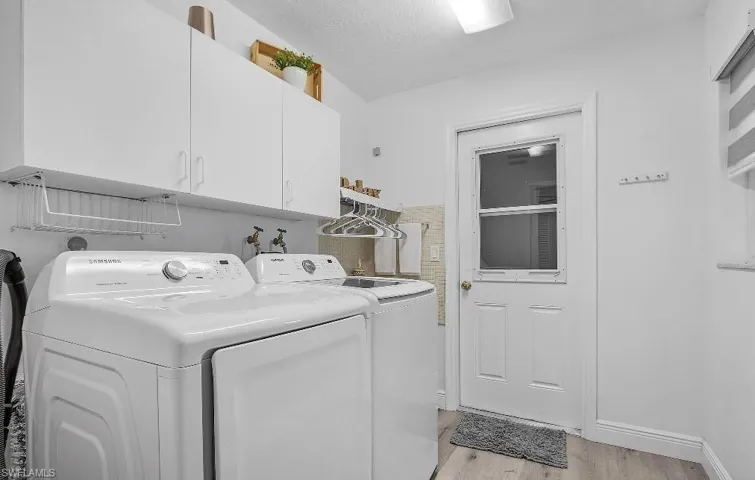 Washroom featuring cabinet space, washer and dryer, and light wood-style flooring