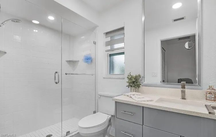 Bathroom with a shower stall, vanity, and recessed lighting