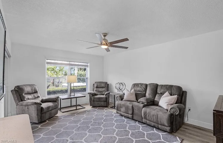 Living room featuring a textured ceiling, wood finished floors, and ceiling fan