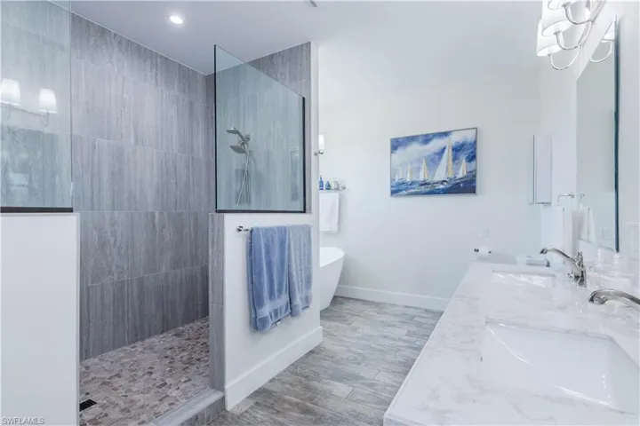 Primary bath featuring a extremely large walk in shower and a freestanding soaking tub