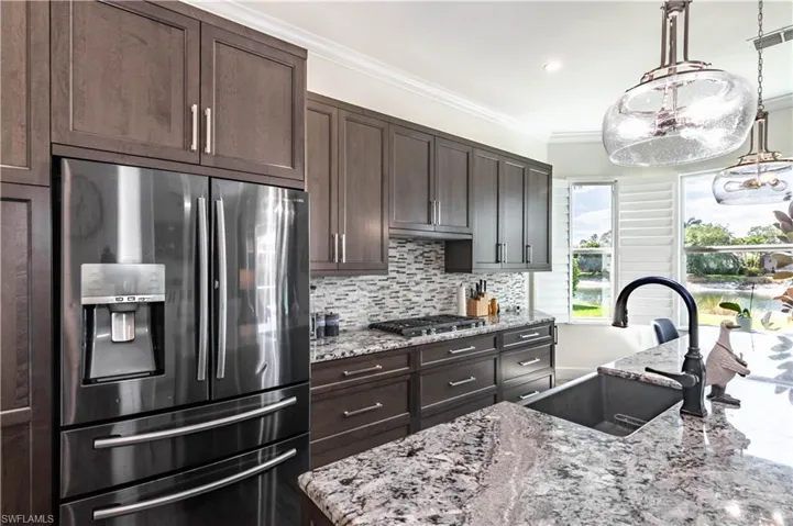 Kitchen featuring stainless steel appliances, a sink, dark brown cabinetry, and decorative backsplash