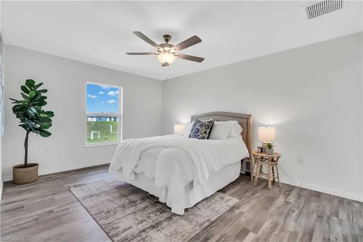 Bedroom with baseboards, visible vents, ceiling fan, and wood finished floors