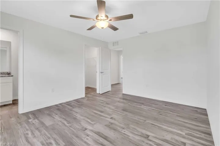 Unfurnished room with baseboards, ceiling fan, visible vents, and light wood-style floors