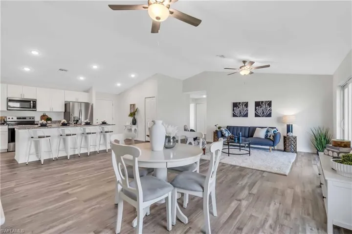 Dining area with lofted ceiling, visible vents, light wood-style flooring, and a ceiling fan