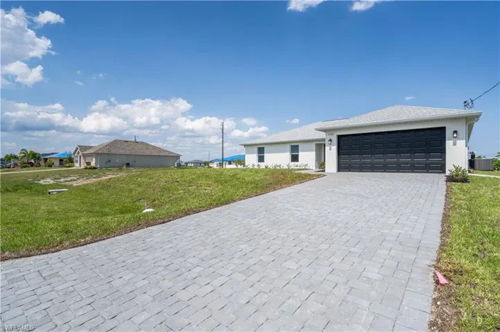 Single story home featuring stucco siding, a front lawn, central AC, and decorative driveway