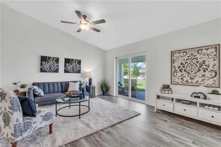 Living area with ceiling fan, wood finished floors, and vaulted ceiling