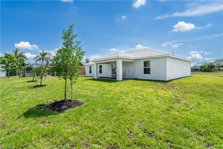 Back of property with stucco siding and a yard