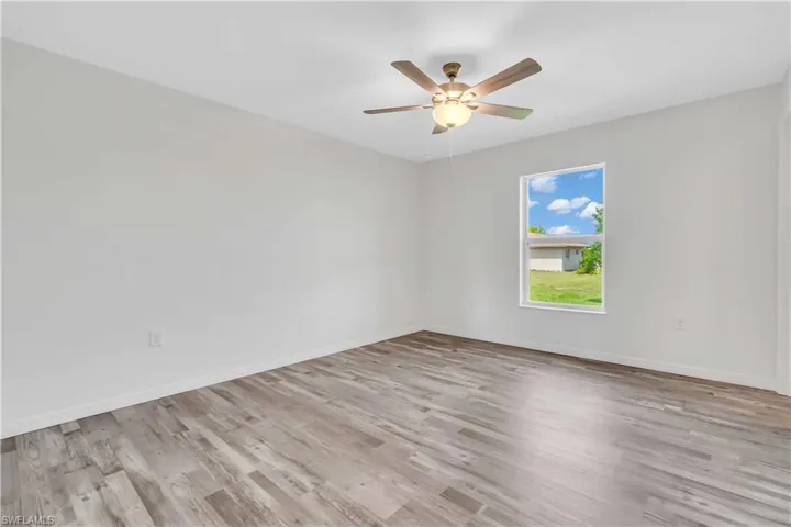 Empty room featuring a ceiling fan, baseboards, and light wood-style flooring