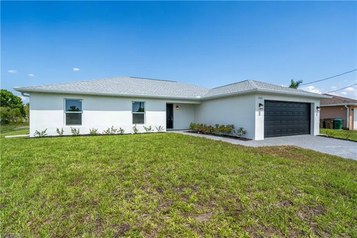 Single story home featuring stucco siding, a garage, a front yard, and decorative driveway