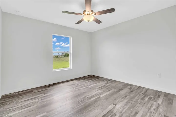 Unfurnished room featuring baseboards, ceiling fan, and wood finished floors