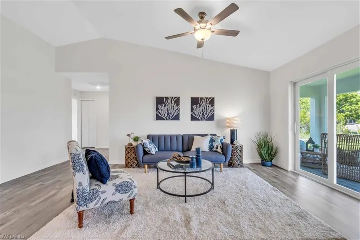 Living area featuring a ceiling fan, baseboards, vaulted ceiling, and wood finished floors