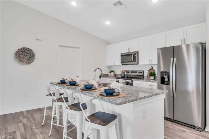 Kitchen with visible vents, white cabinets, a kitchen bar, and stainless steel appliances