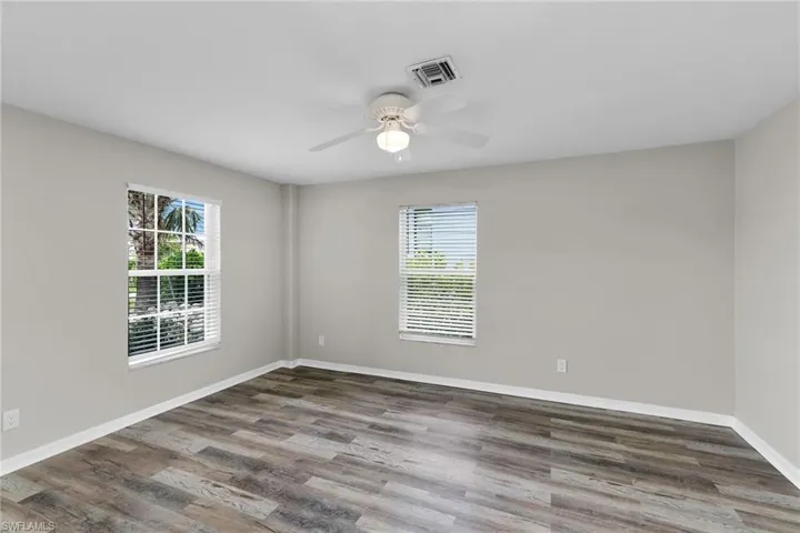 Spare room with plenty of natural light, a ceiling fan, and wood finished floors