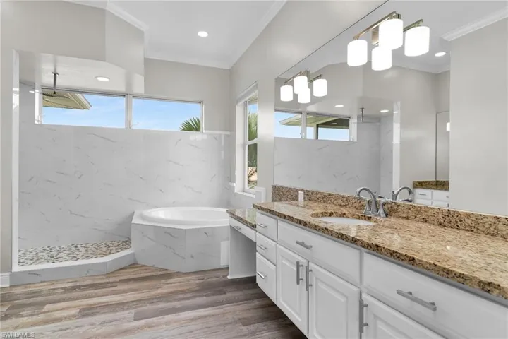 Bathroom featuring ornamental molding, vanity, a garden tub, a marble finish shower, and wood finished floors