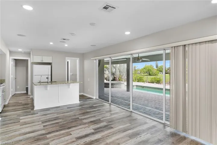 Kitchen featuring freestanding refrigerator, wood finished floors, white cabinetry, light stone counters, and a ceiling fan
