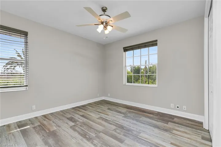 Unfurnished room with healthy amount of natural light, wood finished floors, and ceiling fan
