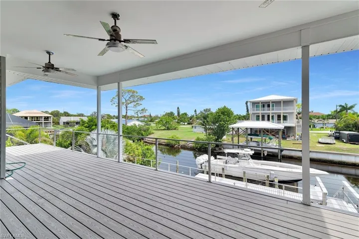 Wooden terrace with a water view, ceiling fan, and a residential view