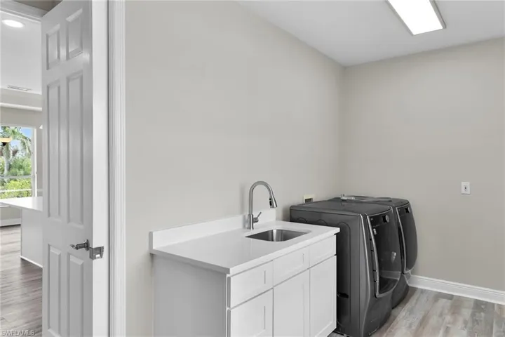 Washroom featuring cabinet space, washer and dryer, light wood-style flooring, and recessed lighting