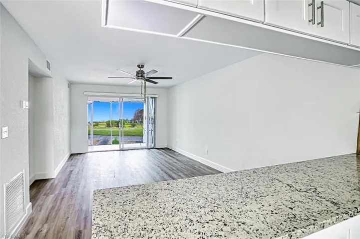 View of living room with entertainment alcove. Granite counters & Luxury Vinyl flooring & Garden view