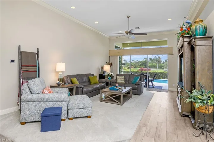 Living room with crown molding, ceiling fan, and wood-type flooring