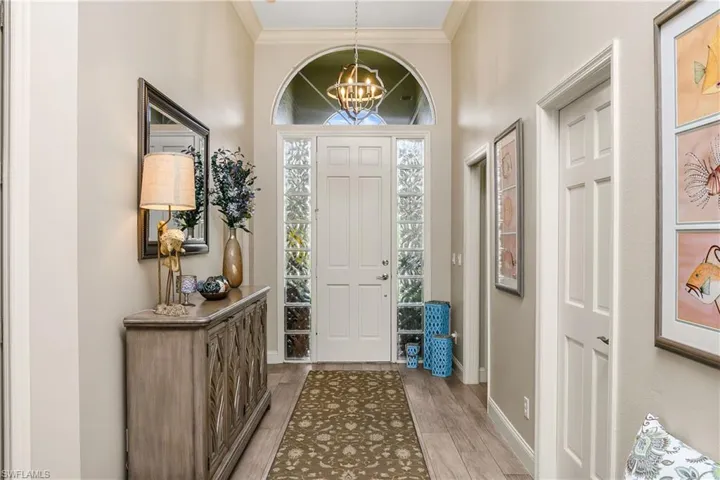 Entryway with an inviting chandelier, wood-type flooring, and ornamental molding