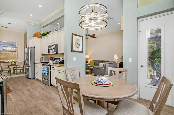 Dining room featuring light wood-type flooring, ceiling fan with notable chandelier, and ornamental molding
