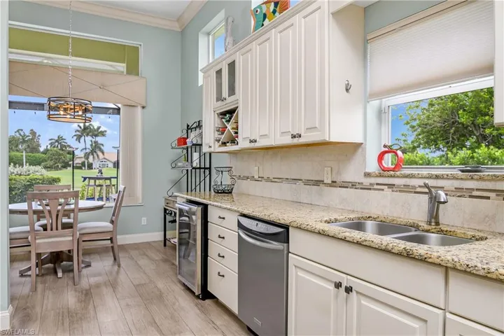 Kitchen featuring stainless steel dishwasher, white cabinetry, light wood-type flooring, sink, and backsplash
