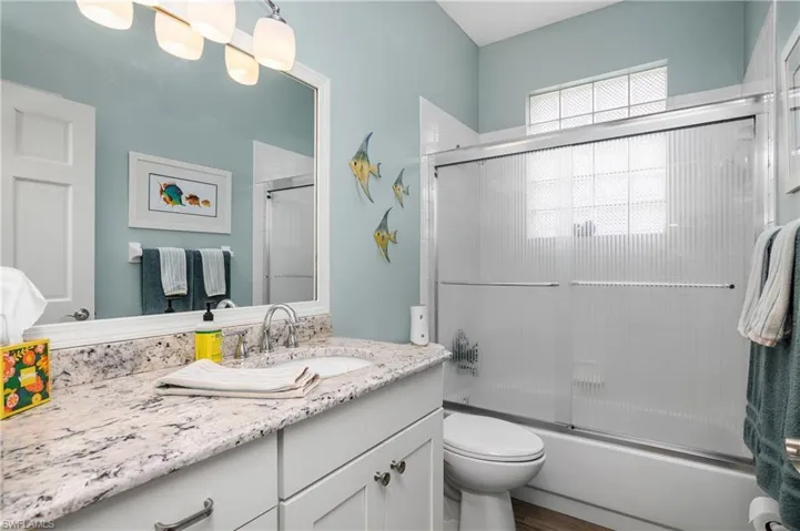 Full bathroom featuring vanity, bath / shower combo with glass door, and toilet