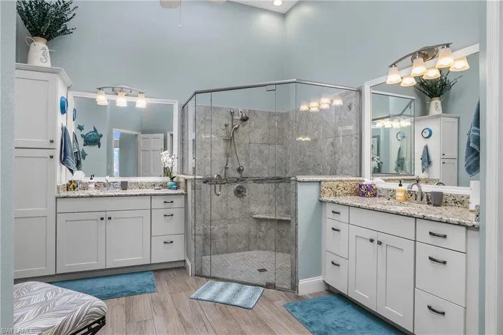 Bathroom with dual vanity, a shower with door, and ceiling fan