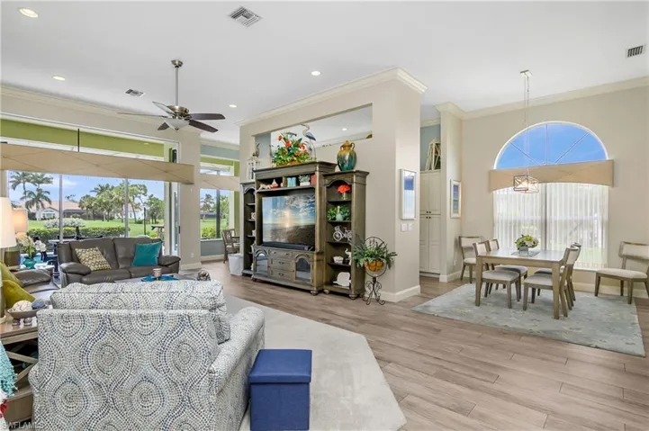 Living room with ornamental molding, ceiling fan, and light wood-type flooring