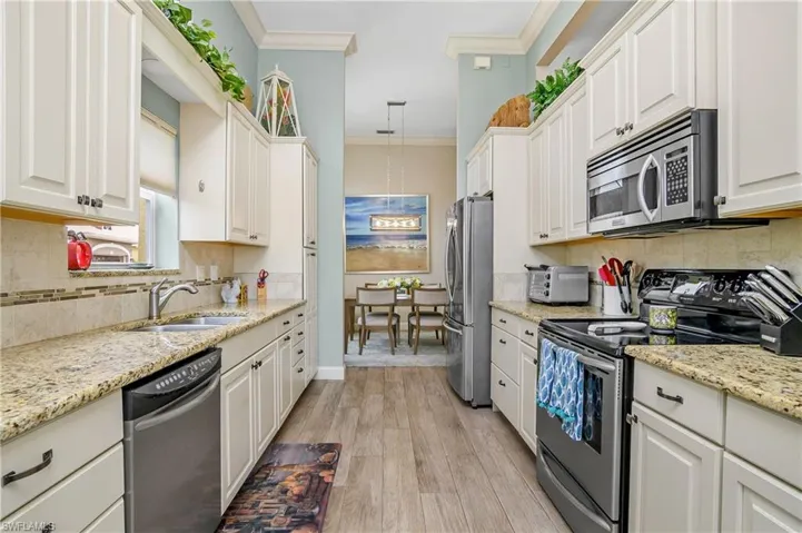 Kitchen featuring white cabinetry, light hardwood / wood-style flooring, tasteful backsplash, appliances with stainless steel finishes, and sink