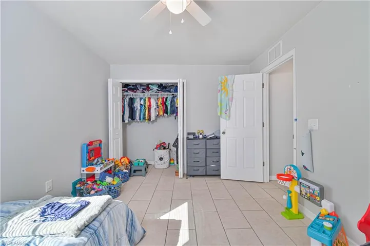 Bedroom with a closet, light tile patterned floors, and ceiling fan